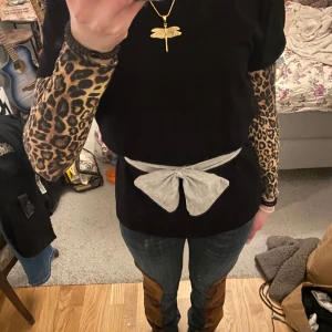 T-shirt med rosett - Svart T-shirt med grå rosett ”skärp” som du knyter runt midjan! Ny! Storlek S, skärpet funkar flera olika storlekar 