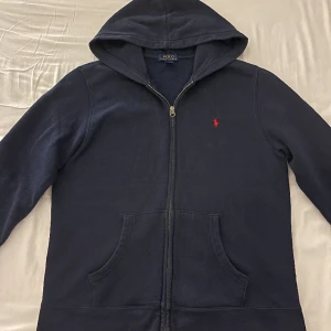Ralph Lauren Zip Hoodie - Polo Ralph Lauren Zip Hoodie (Äkta). Extremt bra kvalitet och knappt använd (ny). Helt felfri inga skador eller fläckar. Snygg design som matchar med allt. Original pris är runt 1700kr säljer min för 800kr! Skirv gärna om du har frågor/ eget bud!  