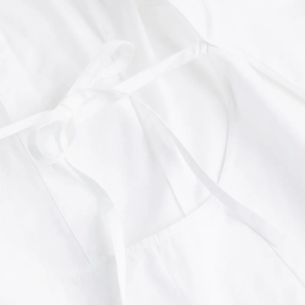 En vit skjorta från H&M med öppen rygg. Aldrig använd och prislapp finns fortfarande kvar.  Den sitter tight i midjan då det finns ett snöre man knyter i ryggen. Skjortor.