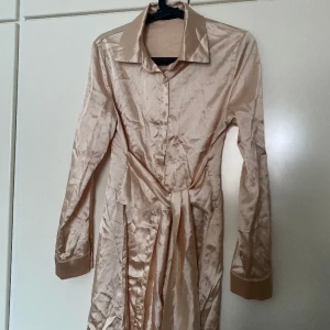 Skjortklänning från Cider - En skjortklänning med knytning som går att knyta både fram och bak. Halkigt material från Cider