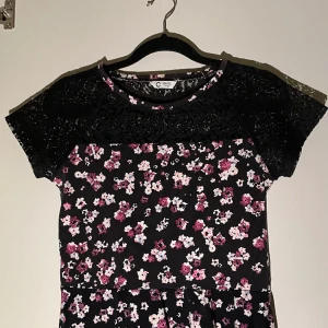 Blommig blus/tröja - Storlek 146/152 men har passat mig i många år. Denna tröjan har en fin passform där nederdelen går ut lite som en kjol, uppe vid axlarna är det spets enligt bilden. 