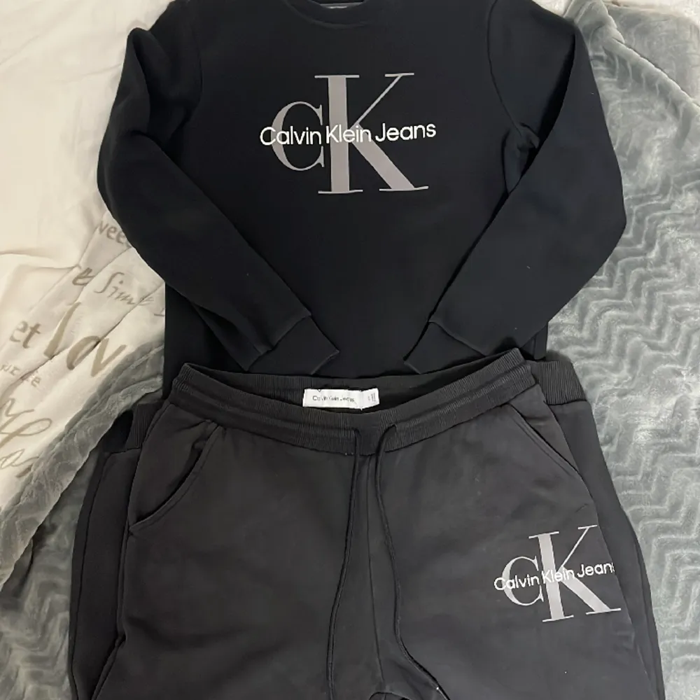 Svart Calvin Klein tracksuit i nyskick. Delarna är köpta tillsammans och har samma färg. Inga defekter eller tecken på användning. Tröjan är i S men stor i storleken. Byxorna i L. . Hoodies.