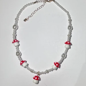 pärl halsband med svampar - ett jättefint pärl halsband med svampar 🍄det är justerbart och den justerbara delen är i guld, även svampen längst ner. använd några fåtal gånger och är i fint skick! frakt 18kr med swish, eller använd köp nu!