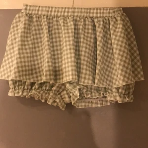 Kjol med mamelucker under M/L, 38-42 - Oanvänd med resår midjan, lätt tyg med kjoldel som sitter fast i midjan med mamelucker under. Resår i benslut.  omkrets midja 74-100 cm, höft 134 cm, benöppning 56-100 cm längd kjoldel 30 cm, byxdel 38 cm,