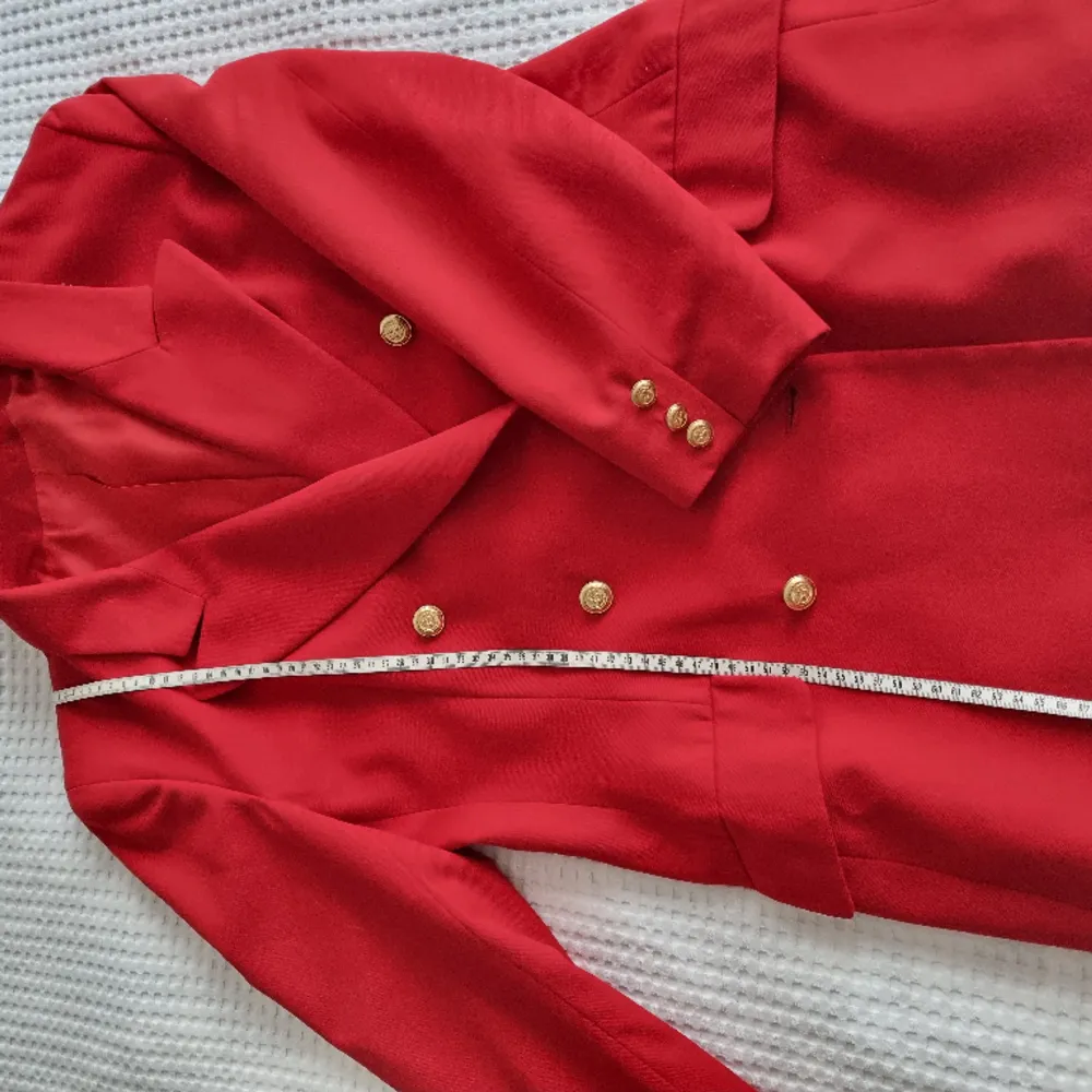 Trä in i kungadömet av hög elegans med denna vintage röda kappa som är här för att regera din garderob. Prydd med guldiga knappar på båda sidor är det inte bara en kappa; det är en majestätiskt modeuttalande. Fantastiskt form . Kostymer.