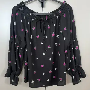 Svart off shoulder blus från Gina Tricot med blommor. 