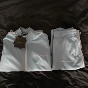 Palm angels tracksuit i en mycket ovanlig färg - Mycket fin tracksuit från Palm angels i en ovanlig färg. Färgen på byxorna och tröjan är ”baby blå” och dressen är i skick 8/10-9/10. Säljer dressen då den inte längre passar. 
