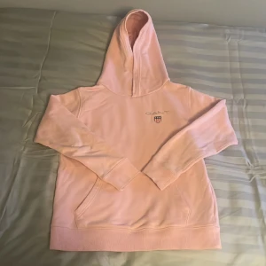Gant Hoodie Rosa - Hoodie från GANT i en ljusrosa nyans.💗 Märkets logga är broderad. Säljer denna för att har växt ur den. Väldigt fint skick! Inga hål eller fläckar.