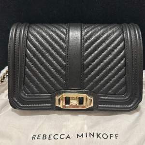 Rebecca Minkoff väska.  En mindre väska i fin kvalite med svart läderband med gulddetajer.  