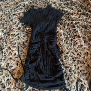 Svart tajt klänning - Storlek 36. Klänningen är från shein men den har inga defekter som visar på dåligt material/kvalitet. Den har snören som går längst både sidorna som man kan knyta.