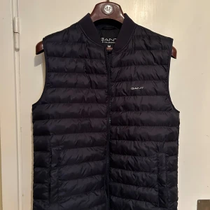 Gant väst - Vi säljer nu denna sjukt snygga GANT dunvästen som passar perfekt för sommarens kyligare dagar men är även ett riktigt kap inför hösten. Skick: 10/10 och är använd endast ett fåtal gånger. Nypris: 2100kr, vårt pris: BARA 399kr! Kontakta vid ev frågor