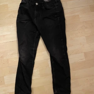 Svarta jeansbyxor - Säljer ett par svarta jeansbyxor i bra skick. De har en klassisk femficksdesign och stängs med en knapp och dragkedja. Perfekta för både vardag och fest!