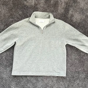 Grå  tröja från TOPMAN - Säljer en supermysig grå fleece tröja från TOPMAN. Den har en halv dragkedja framtill och en hög krage som håller dig varm. Perfekt för kyliga dagar! Tröjan är 7/10 i skick och har långa ärmar. Passar perfekt till höst och vinter.
