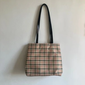 Rutig axelremsväska vintage  - Rutig väska med svarta axelremmar,  inköpt vintage på butik i Stockholm. Mått 20x20 cm. Jättebra skick, använd ett fåtal gånger. Varumärke Duffy. 