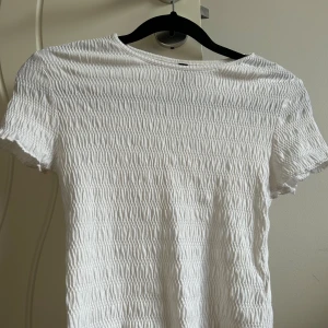 Tshirt med textur 🤍 - En croppad tshirt ifrån H&M, använt endast en gång på en Harry Styles konsert!! Finns endast en liten missfärgning runt kragen, men det är inget som syns när man har på sig toppen. Hör av er vid frågor 🩵
