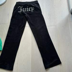 Svarta byxor från Juicy Couture med texten 'Juicy' i glittriga bokstäver på baksidan. Byxorna har en rak passform och är tillverkade i ett mjukt material. endast använda 1 gång.