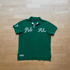 Säljer en snygg grön Polo RL t-shirt i storlek L. Den har korta ärmar och är gjord av bomull. T-shirten har en klassisk krage och vita broderade bokstäver 'Polo' och 'RL' på framsidan. Perfekt för en avslappnad och stilren look!