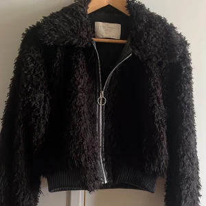 Svart teddyjacka med dragkedja - Säljer en supermysig svart teddyjacka från Zara i storlek S. Jackan har en dragkedja framtill och är perfekt för höst och vinter. Den är i nyskick och har långa ärmar. Perfekt för att hålla sig varm och stilren under de kallare månaderna!