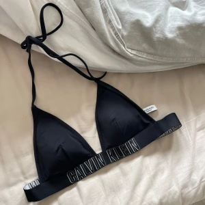 Calvin Klein bikinitopp  - Säljer denna bikiniöverdel från Calvin Klein. Svart med svart text, helt i nyskick. Andra bilden är lånad!🥰