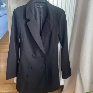 Lång kavaj stl xs  - Lång dubbelknäppt helfodrad kavaj från SHEIN stl xs. Längd 80 cm, midjan 75cm. Plagget är ostruket efter att ha varit nedpackat.