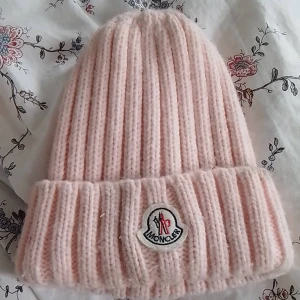 Moncler mössa  - Säljer en rosa Moncler mössa. Bollen har hoppat av men man kan säkert sy fast den på något sätt eller bara ha den som den är. Annars är den i bra skick förutom att det finns en liten fläck (man kan få bort den). Säljer den för 500kr + frakt! 