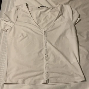 Blus med knappar - Vit topp med knappar. Använd några gånger men är i bra skick.