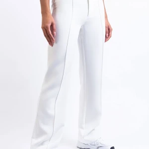 Mid Waist Kostymbyxor Utan Fickor - Hazel White  - Mid waist kostymbyxor med raka ben och stråveck. Inga fickor. Bälteshällor som passar både smalare och bredare bälten. Byxorna stängs med dragkedja, hake och gömd knapp.   Ej använd pga storlek. 