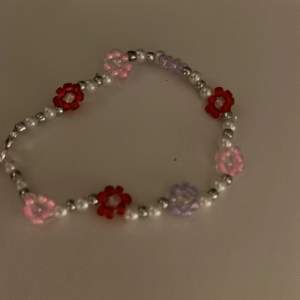 Handgjort armband med rosa, röda och lila blommor. Ca 17 cm 