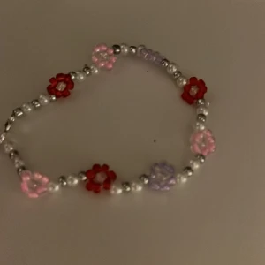 Pärlarmband - Handgjort armband med rosa, röda och lila blommor. Ca 17 cm 