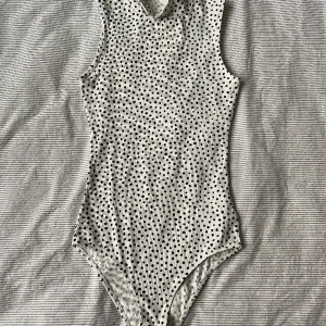 Prickig polobody  - En jättefin body köpt på HM! Den sitter superfint på och är jätteskön till ett par låga jeans då man slipper riskera att visa trosorna!