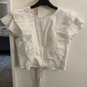 Vit volangtopp  - Supersöt vit volangtopp från NAKD. Inga defekter i storlek 32🤍 Knyten i ryggen där man själv kan bestämma storlek och hur rajt man vill ha den. Nypris ca 340kr<3