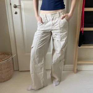 Lågmidjade cargo byxor Y2K  - Ett par slutsålda lågmidjade beige-vita cargobyxor från Urban Outfitters! De är sparsamt använda och har inga defekter💗nypris 750kr! 🎀