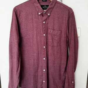 Rödrosa herrskjorta - En skjorta från hollister i fint skick. Använd ett fåtal par gånger. Slimfit. Rödrosavit. Axelbredd 45 cm och Längd 77 cm. Storlek  M.
