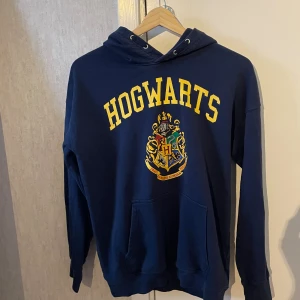 En mörkblå hoodie med en symbol och gul text - Bara använt några gånger 