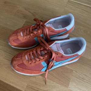 Onitsuka Tiger EDR 78 - Onistuka Tiger sneakers i nyskick, storlek 39. Endast provade men ej använda.   I orange tyg med turkosblå ränder och blekrosa innersula.