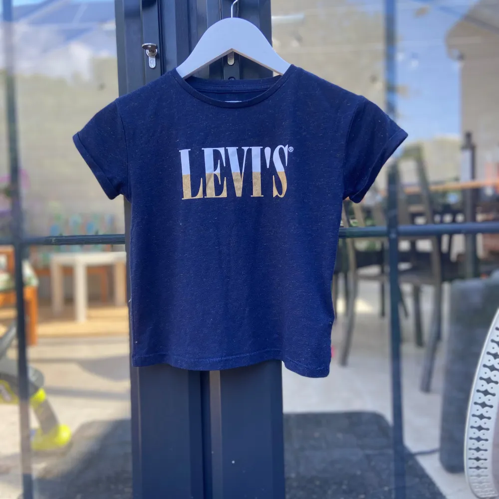 En mörkblå Levi’s t-shirt med guldstänk i storlek 128.. T-shirts.