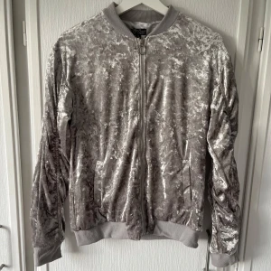 Silvrig kofta - Fin silvrig kofta. Väldigt mjukt tyg på utsidan. Använd flera gånger. I mycket bra skick. Bekväm. 