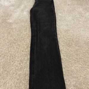 Jeans - Svarta jeans, avklippta så de passar någon runt 160. Finns två knappar där uppe som man kan välja mellan.