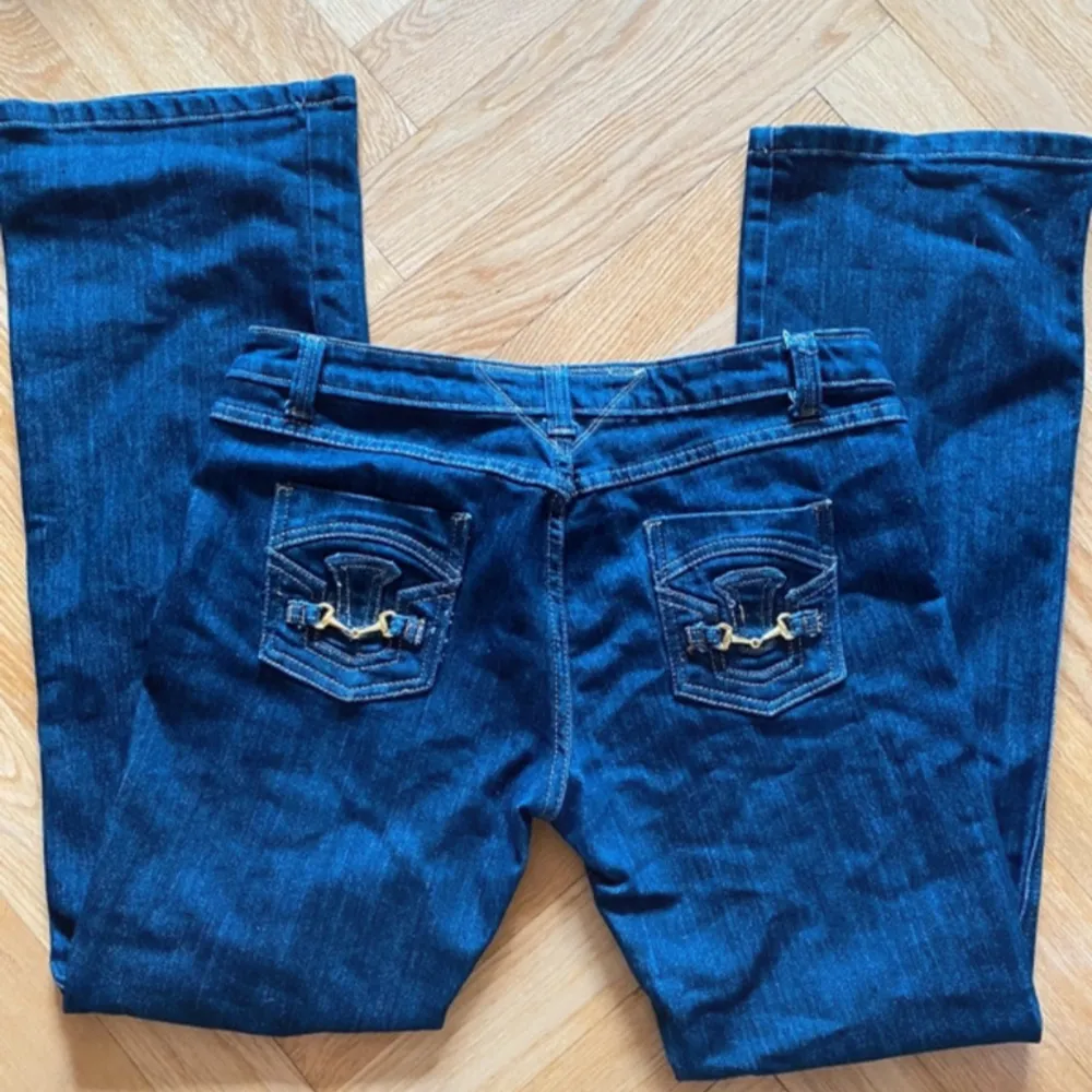 Snygga mörkblå low waist jeans med gulddetaljer och bootcut. Köpta second hand men aldrig använda.. Jeans & Byxor.
