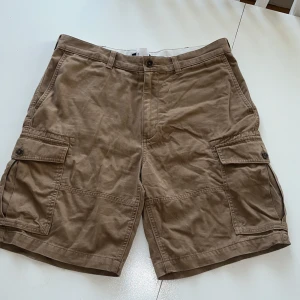 Cargo shorts bruna - Bruna cargo-shorts från Lands' End i storlek 34 med många fickor. Passformen är ”traditionell” och materialet är gjort av 100% bomull. Pris kan diskuteras.