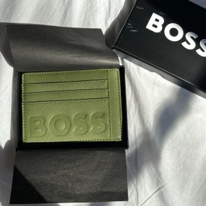 Hugo Boss plånbok - Snygg grön plånbok från Hugo Boss. Den är i nyskick och aldig använd. Den har flera fack och ett av dem har dragkedja. Lådan tillkommer. Säljer då den inte kommer till användning. Nypris är ca 1200kr. Priset är diskuterbart. Köparen står för frakten.