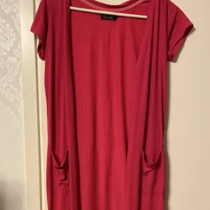 Lång rosa härlig sommarkofta strl XS/34 - Längre modell i tunt tyg.  Säljes i begagnat skick. Kolla gärna in mina andra annonser, jag samfraktar.