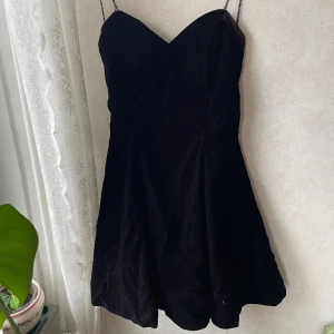 Vintage sammet cocktailklänning - Svart cocktailklänning med tyll underkjol, sammet och spetsband. Strukturerad korsett modell OBS-missfärgning (se bild) och axelbanden är slitna  Köpt för 800kr på Beyond Retro