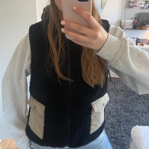 Teddyväst - Svart teddyväst med beiga fickor, perfekt för våren💐