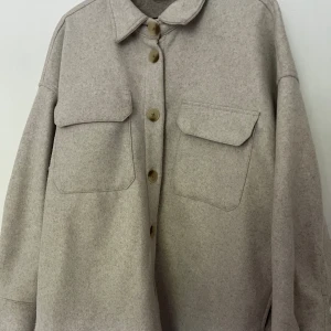 Beige Schacket - Stl: L Köptes i Irland 2022 Efter att jag haft på mig den 4-7 ggr insåg jag att den var för oversized för mig. Jag brukar vanligtvis ha stl:S. Har mest hängt i garderoben sen dess. 100% polyester 