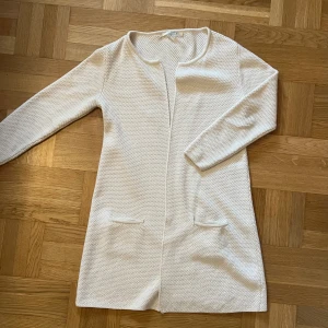 Kofta - Lång, öppen, kofta Dansk design. Bra skick, sparsamt använd. Merino ull/akryl (50/50). Räcker ned till knä (Nypris 1495kr)