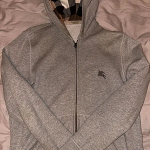 Burberry Zip - Säljer nu min tvärfeta Burberry zipup. Skicket är OK, själva tröjan är i bra skick men finns små hål som man knappt märker av. Huvan är lite bökig då det inte finns några snören. Storleken är L. 