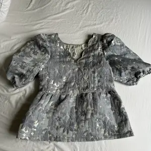 A pretty blouse in good condition. Only used a few times. Silver and blue. New price 800,-