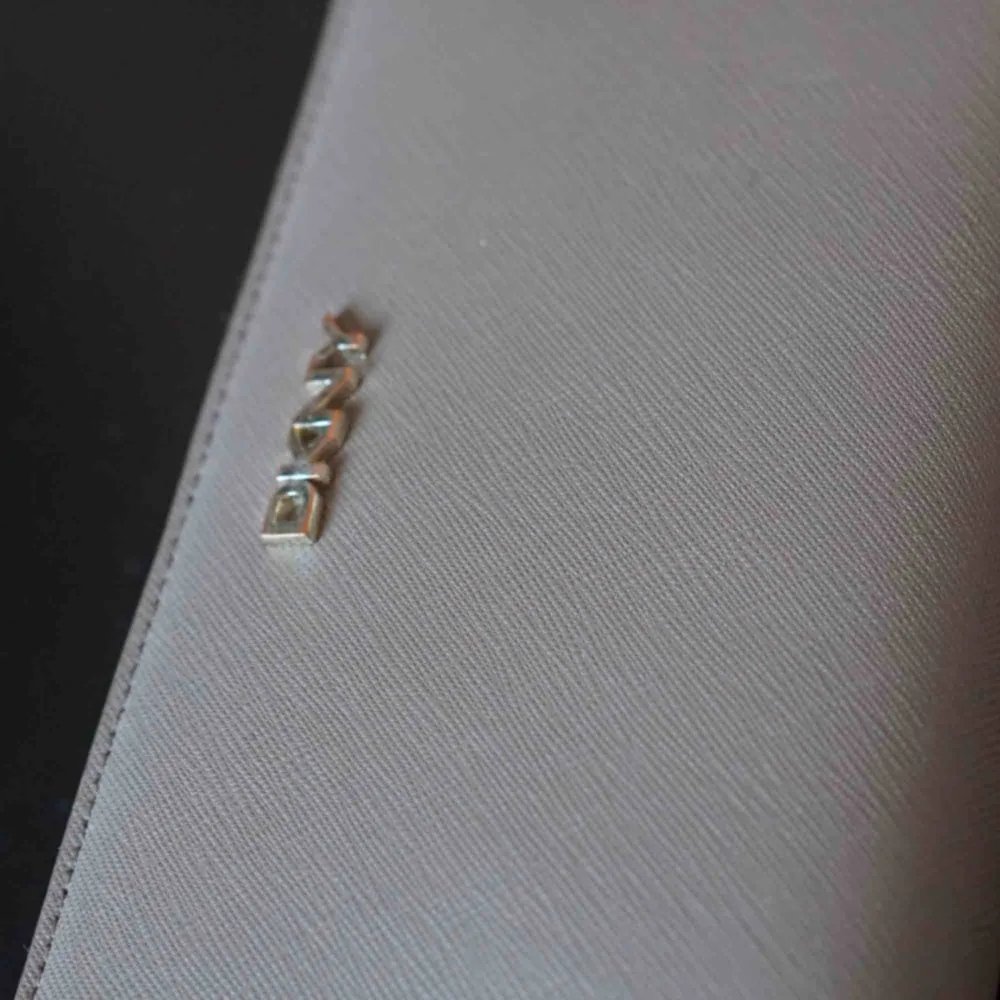  Beige DKNY plånbok. Har ej kvar kvitto, men plånboken är äkta och inköpt i Dubai för antal år sedan. Guldet har börjat tappa sin färg, men är i  399 kr ex frakt eller mötas i Stockholm för 399 kr.  Varan finns på andra köp och sälj sidor 🌟. Accessoarer.