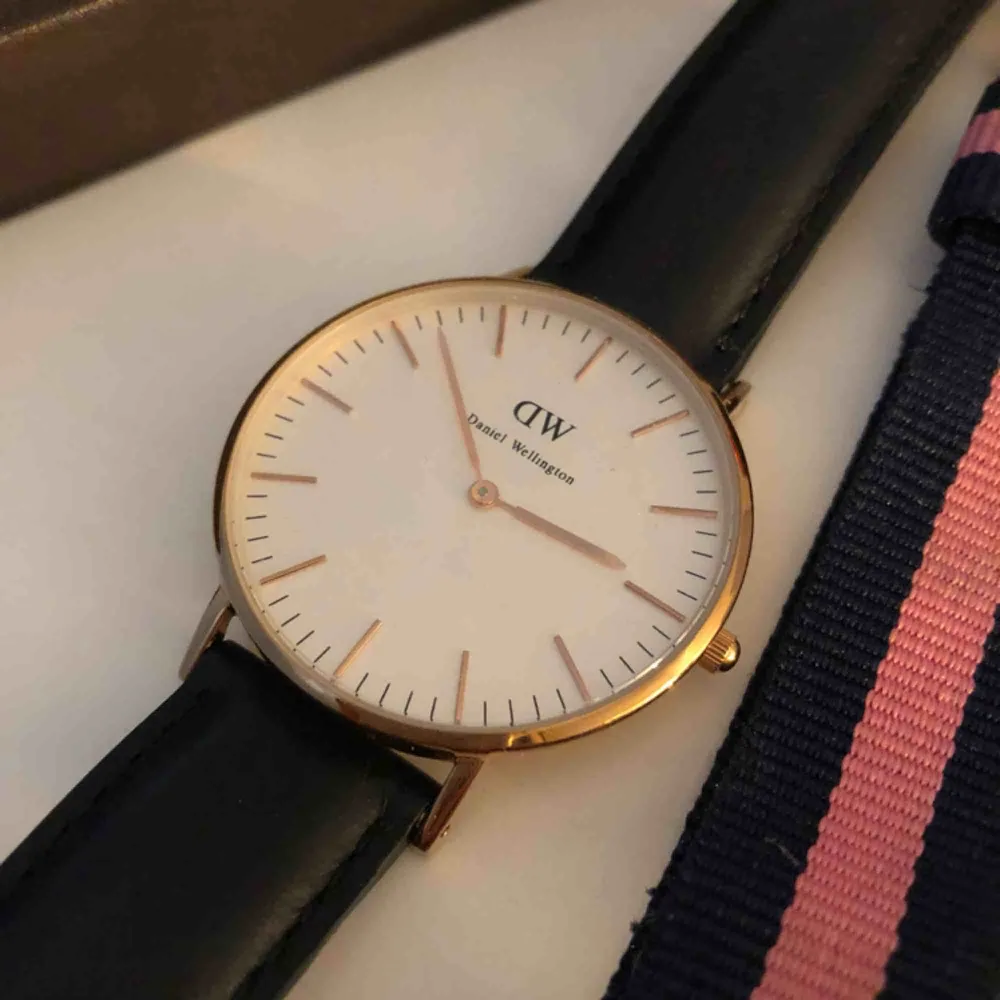 Äkta Daniel Wellington klocka i roseguld med svart läderarmband och ett tillhörande rosa med blåränder. Sparsamt använd.. Accessoarer.